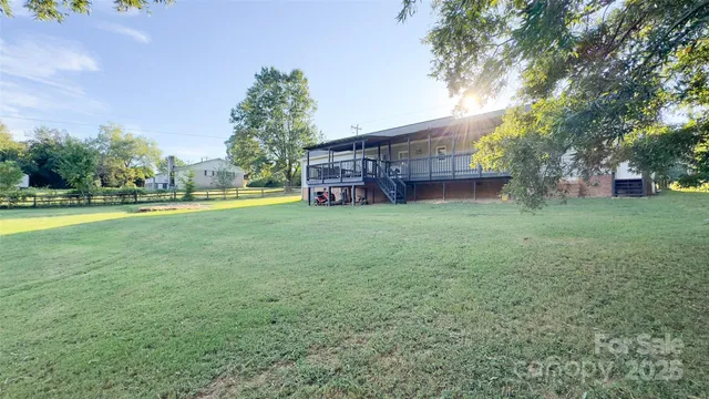 a view of a house with a big yard and large trees