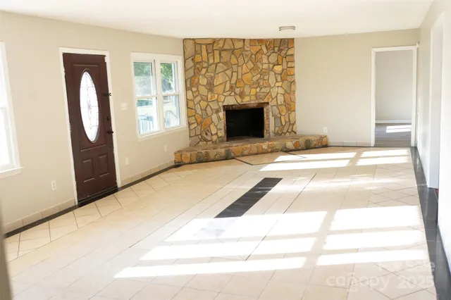 a view of an empty room with fireplace and a window