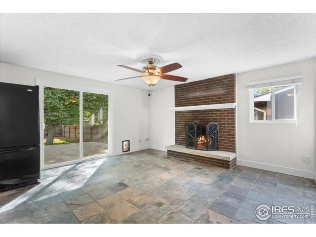 a view of an empty room with a fireplace and a ceiling fan