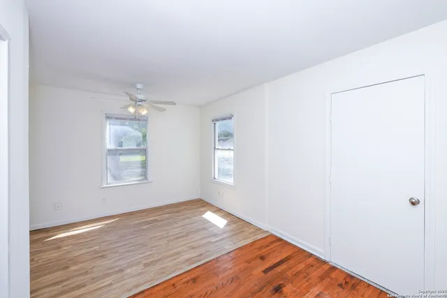 a view of an empty room with wooden floor and a window