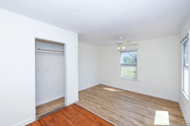 an empty room with wooden floor and windows