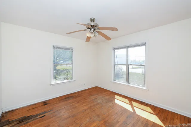 an empty room with windows and fan