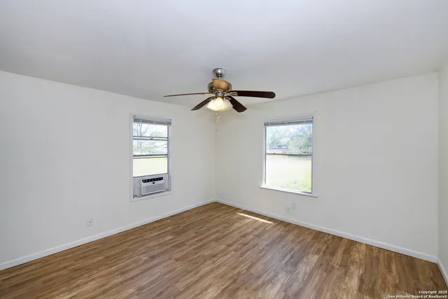a view of empty room with wooden floor and fan