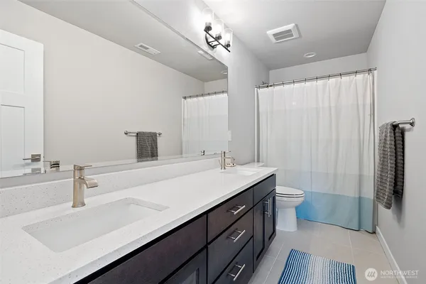 a bathroom with a double vanity sink a toilet and a tub