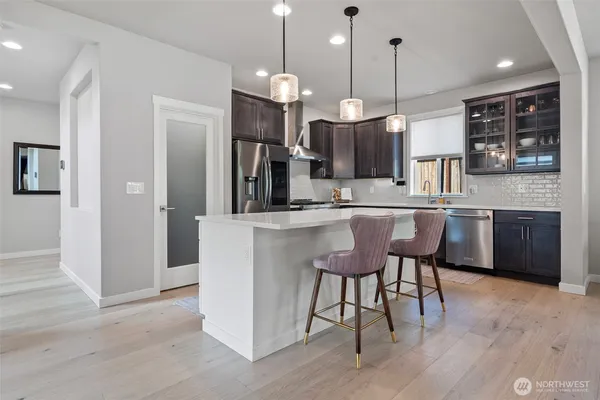 a kitchen with kitchen island granite countertop a sink a counter space appliances and cabinets
