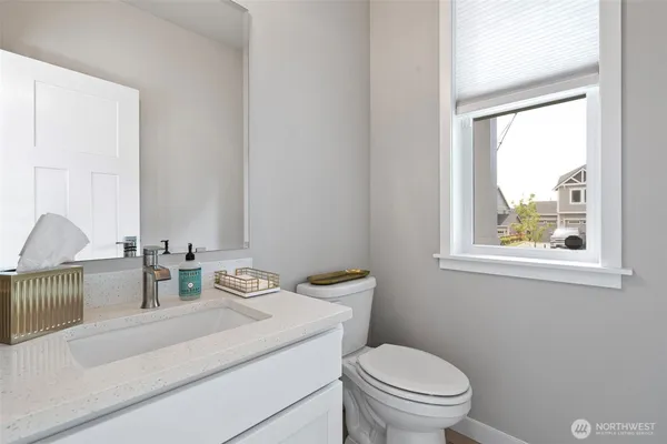 a bathroom with a granite countertop sink mirror vanity and toilet