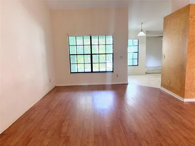 an empty room with wooden floor and windows