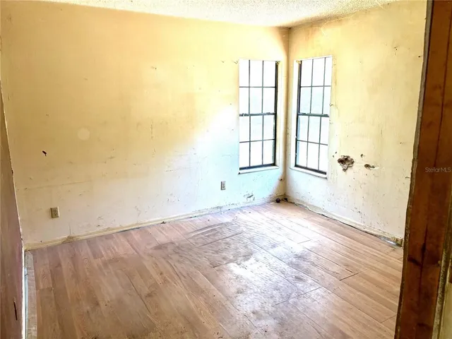 an empty room with wooden floor and windows