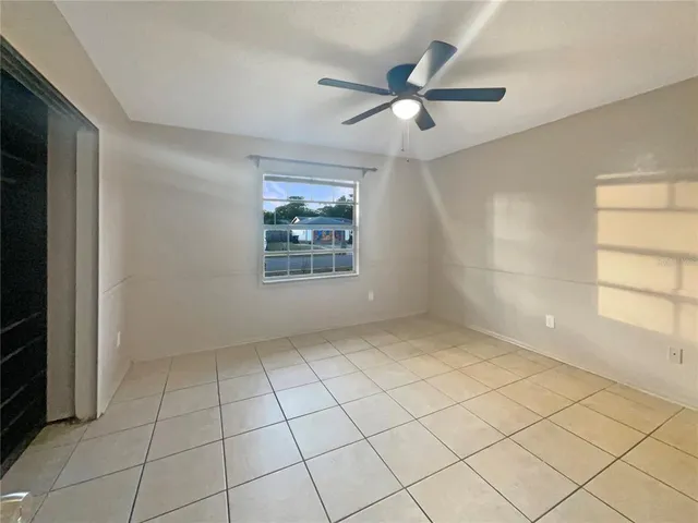 an empty room with windows and fan