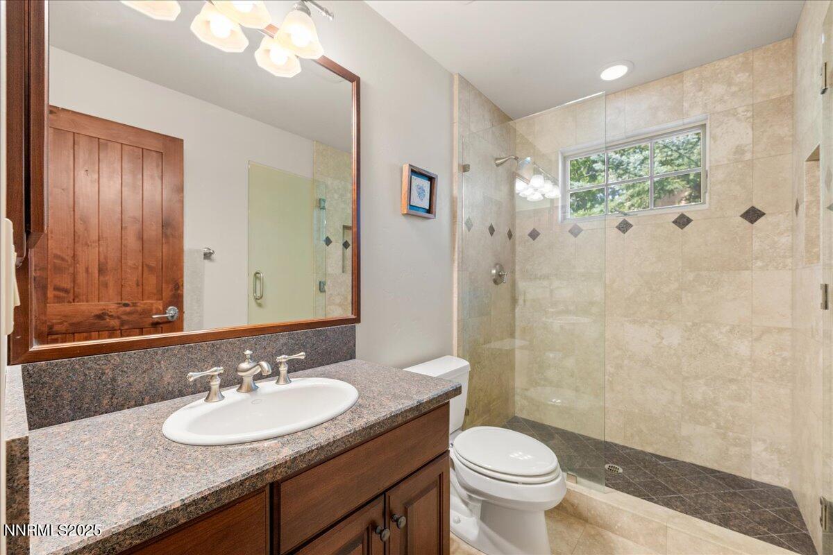 6355 Wetzel Court Reno, NV 89511 - Photo 24 of 38 a bathroom with a granite countertop sink toilet a large mirror and shower