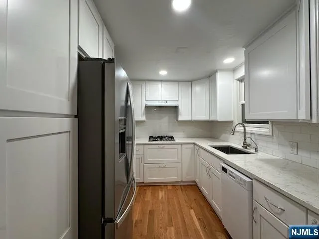a kitchen with a sink a refrigerator and cabinets