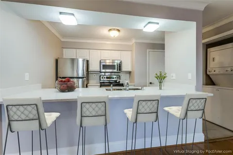 a kitchen with stainless steel appliances a dining table chairs refrigerator and microwave
