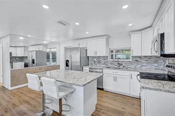 a kitchen with granite countertop kitchen island wooden cabinets and refrigerator