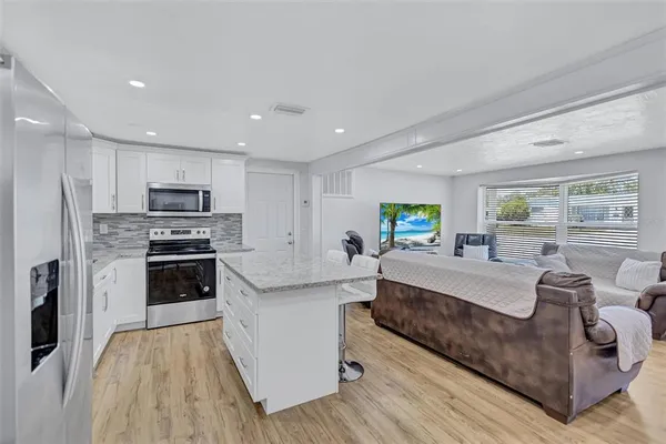 a large living room with stainless steel appliances granite countertop a couch and a stove top oven