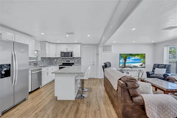 a living room with stainless steel appliances furniture and a flat screen tv