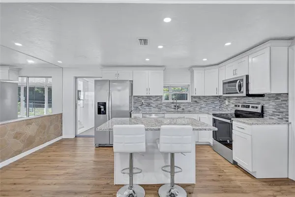 a large open kitchen with a refrigerator a stove a sink a dining table and chairs