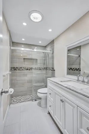 a bathroom with a granite countertop sink mirror and toilet
