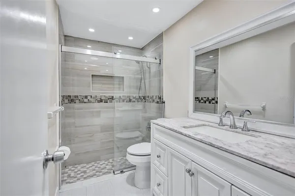 a bathroom with a granite countertop sink a toilet and a shower