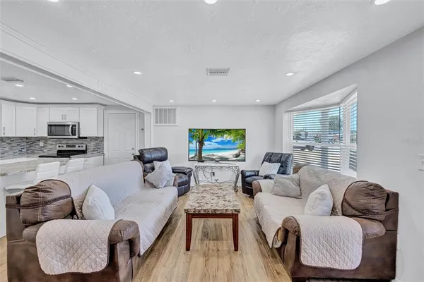 a living room with furniture kitchen view and a large window