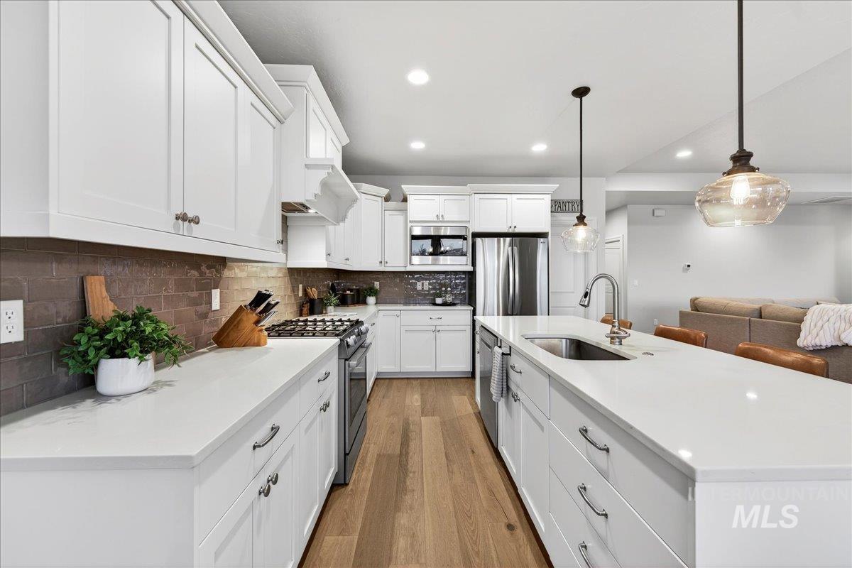 24813 Valley Run Place Star, ID 83669 - Photo 13 of 50 Kitchen featuring a kitchen island with sink, pendant lighting, stainless steel appliances, white cabinets, and recessed lighting