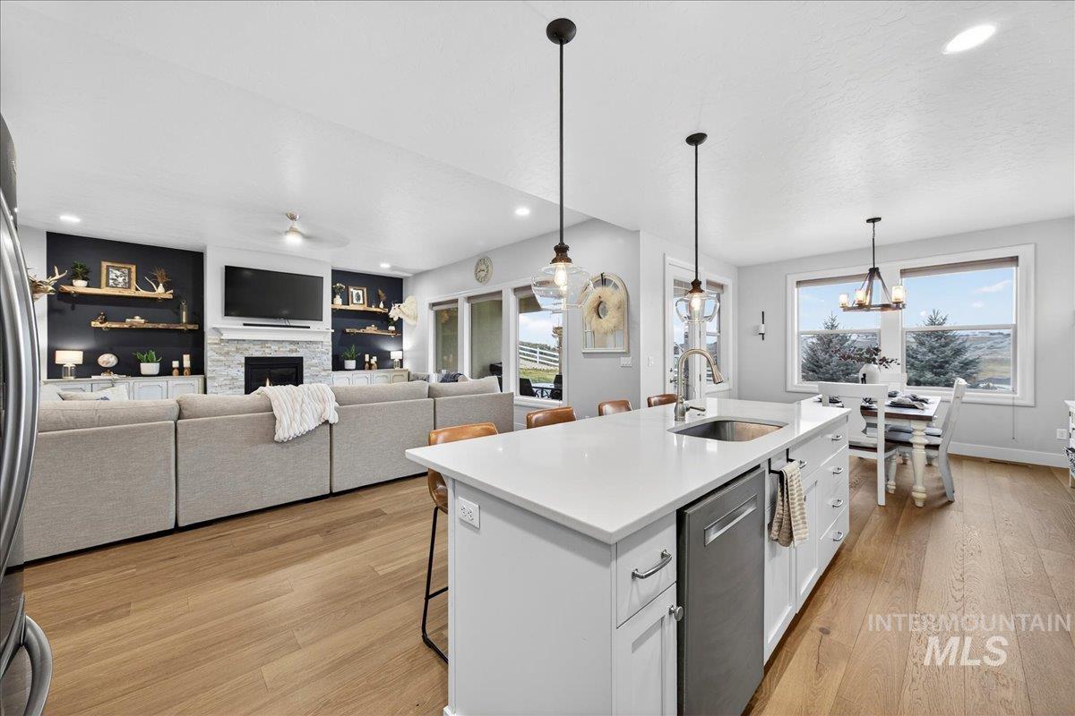 24813 Valley Run Place Star, ID 83669 - Photo 14 of 50 Kitchen featuring a kitchen bar, a fireplace, a center island with sink, light wood finished floors, and stainless steel appliances
