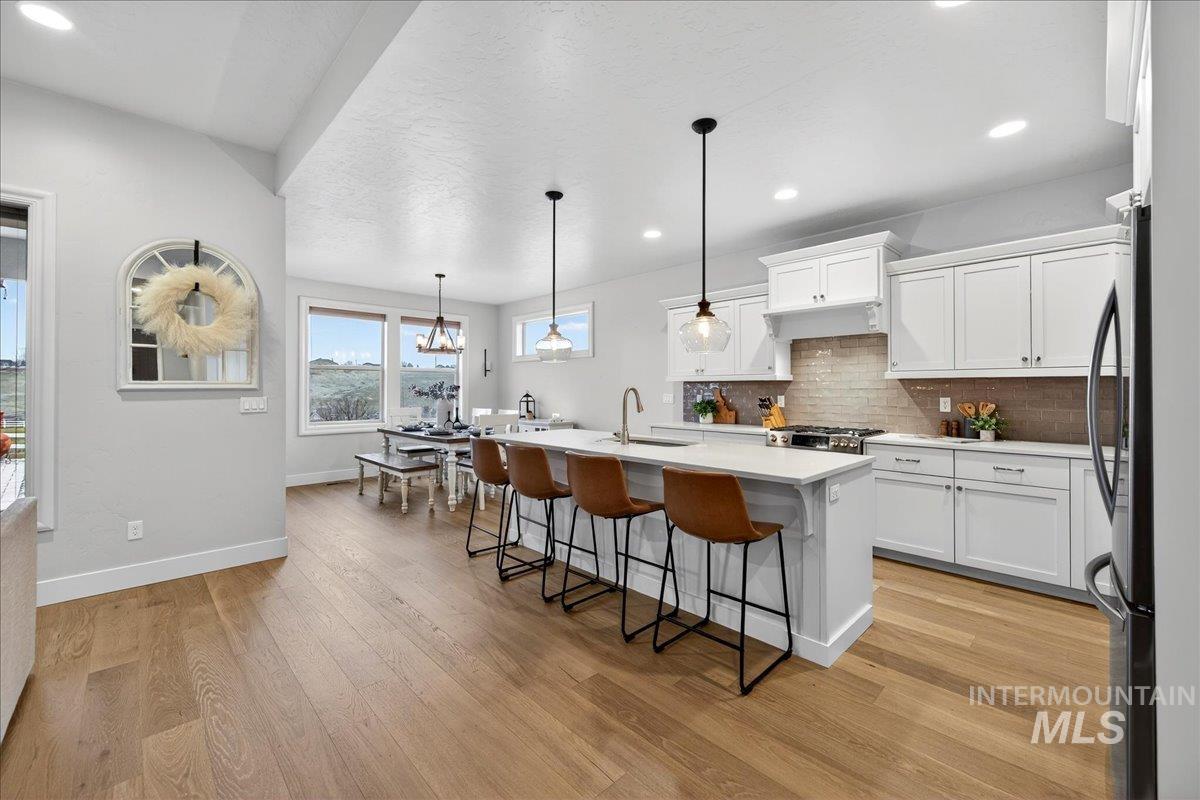 24813 Valley Run Place Star, ID 83669 - Photo 15 of 50 Kitchen featuring a kitchen bar, a chandelier, a center island with sink, hanging light fixtures, and white cabinetry