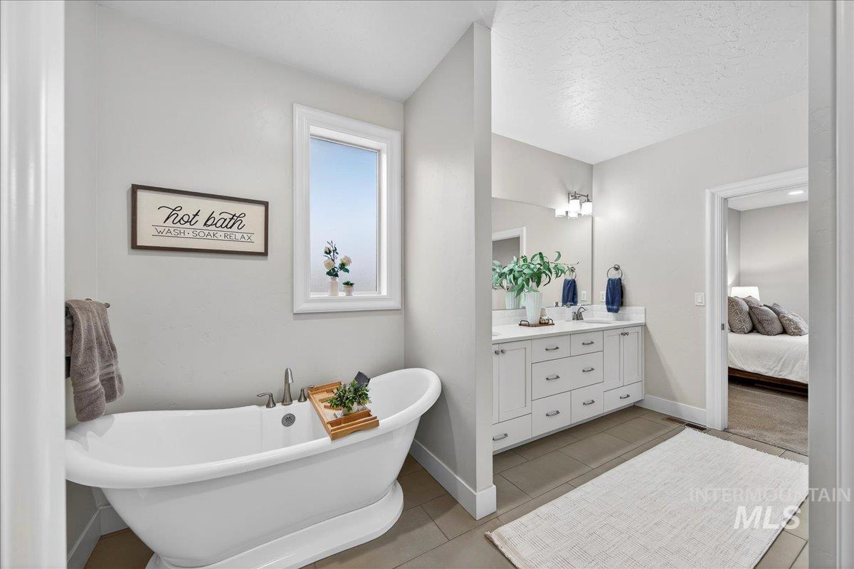 24813 Valley Run Place Star, ID 83669 - Photo 31 of 50 Full bath featuring double vanity, a freestanding tub, ensuite bathroom, light tile patterned flooring, and a textured ceiling