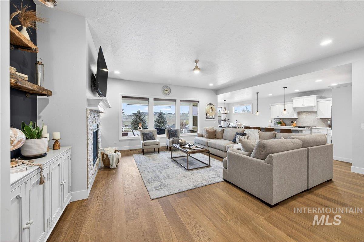 24813 Valley Run Place Star, ID 83669 - Photo 8 of 50 Living area featuring a stone fireplace, light wood-style flooring, a textured ceiling, and recessed lighting