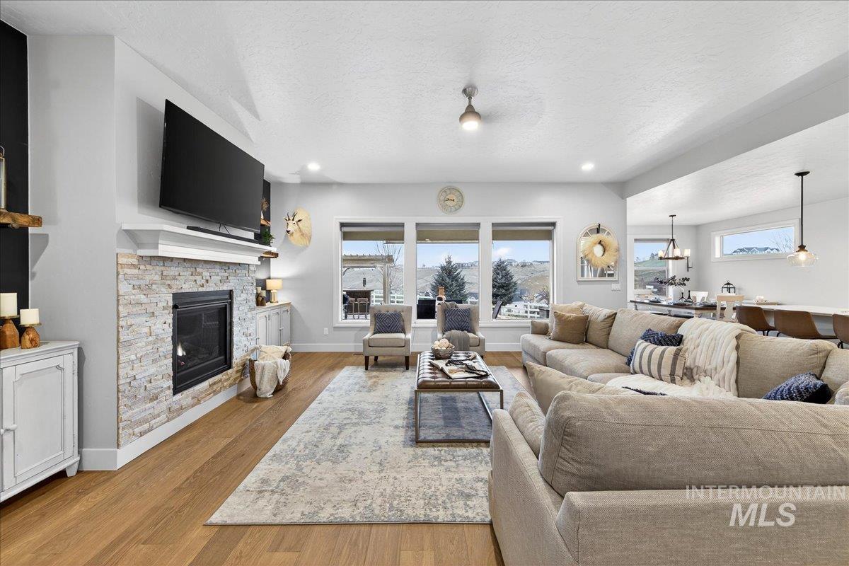 24813 Valley Run Place Star, ID 83669 - Photo 10 of 50 Living room with a fireplace, healthy amount of natural light, wood finished floors, a textured ceiling, and recessed lighting