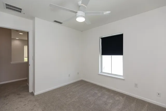 an empty room with a window and a fan