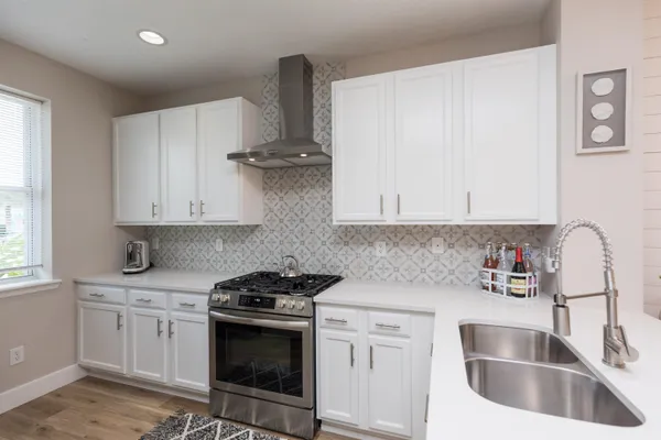 a kitchen with stainless steel appliances granite countertop a sink stove and white cabinets