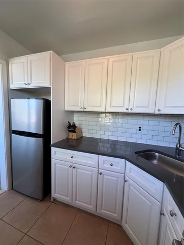 a kitchen with white cabinets and refrigerator