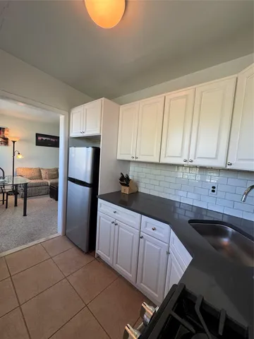 a kitchen with granite countertop a refrigerator and a stove top oven