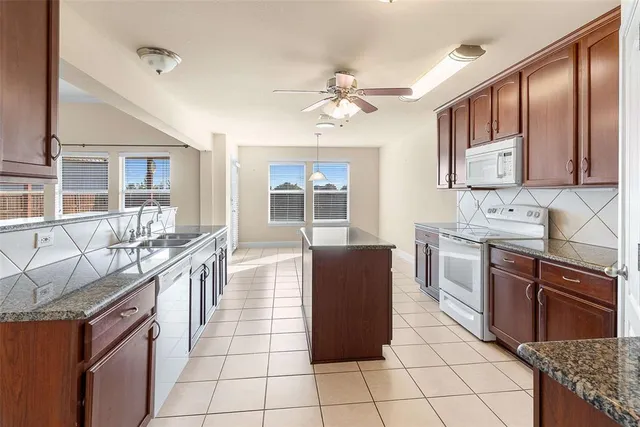 a kitchen with stainless steel appliances granite countertop a stove top oven a sink dishwasher a dining table and chairs with wooden floor