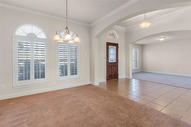 a view of an empty room with a window and a kitchen