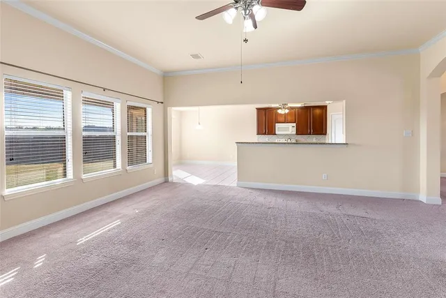 a view of an empty room with a window and a kitchen