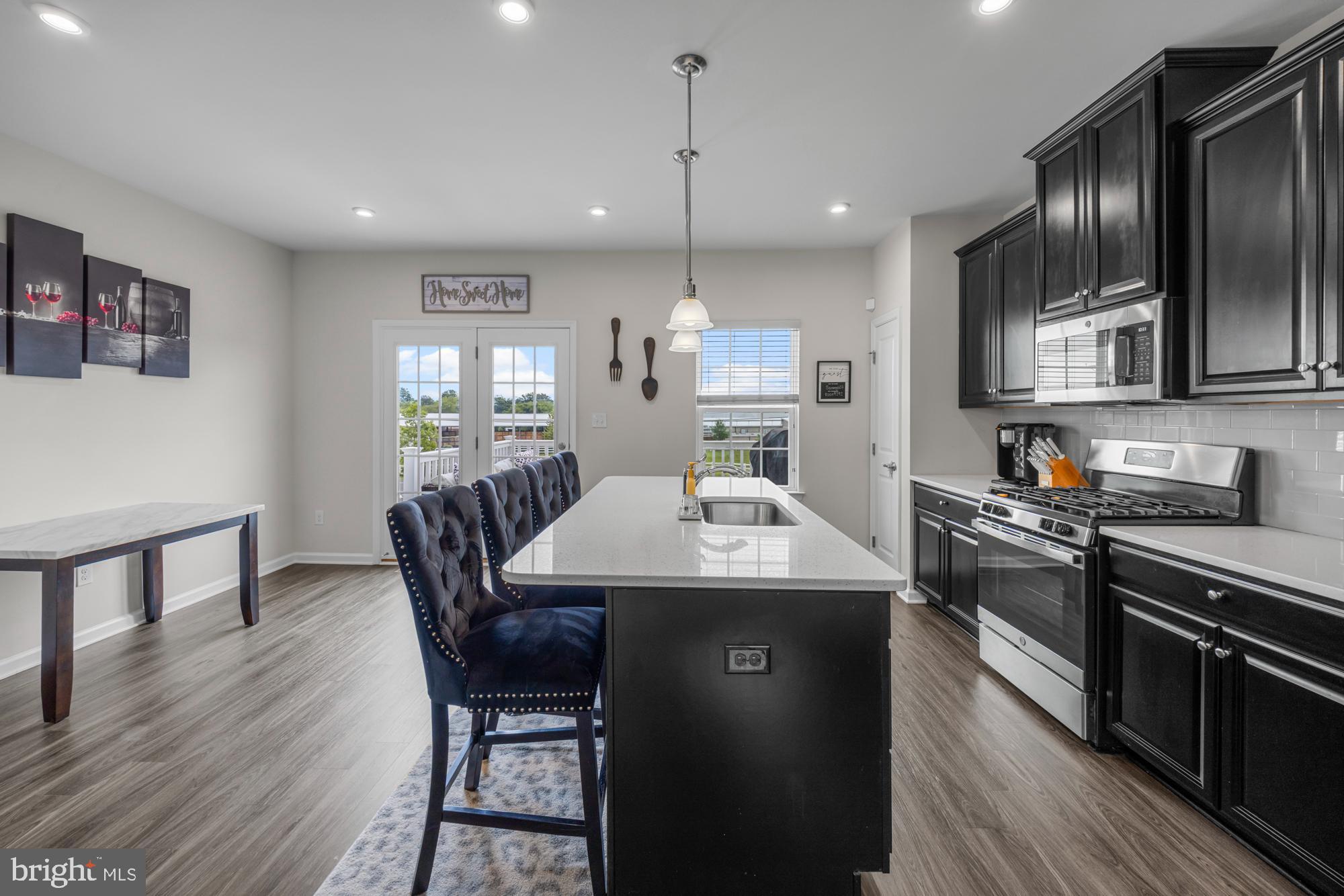 607 Sammy Street Swedesboro, NJ 08085 - Photo 13 of 37 a kitchen with stainless steel appliances granite countertop a kitchen island hardwood floor sink stove dining table and chairs