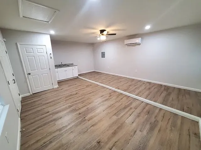an empty room with wooden floor ceiling fan and window