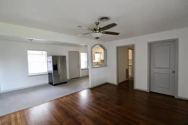 a view of an empty room with window and wooden floor