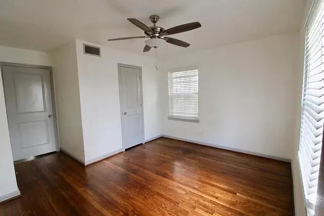 an empty room with wooden floor and windows