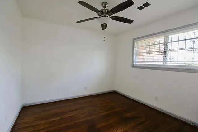 an empty room with a window and a ceiling fan