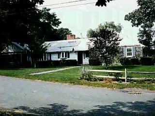 a view of a house next to a yard with big trees