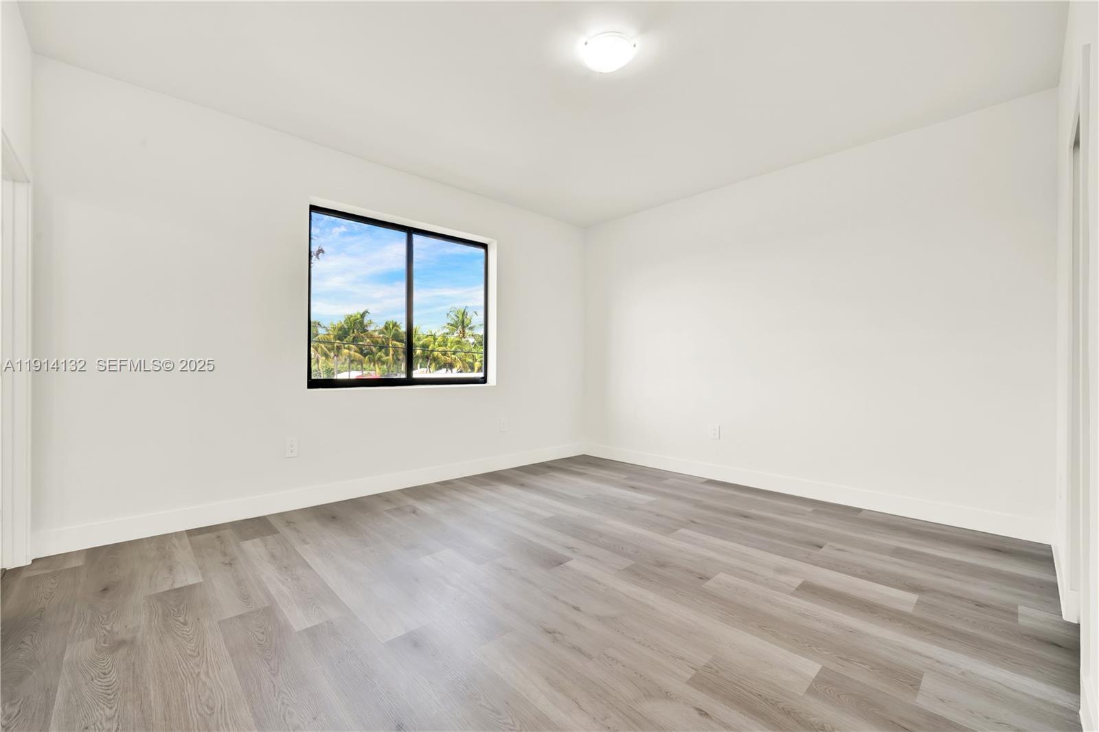 34520 Southwest 191st Court, Unit 34520 Homestead, FL 33034 - Photo 29 of 37 an empty room with wooden floor and windows