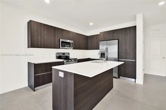 a kitchen with kitchen island a sink refrigerator and microwave
