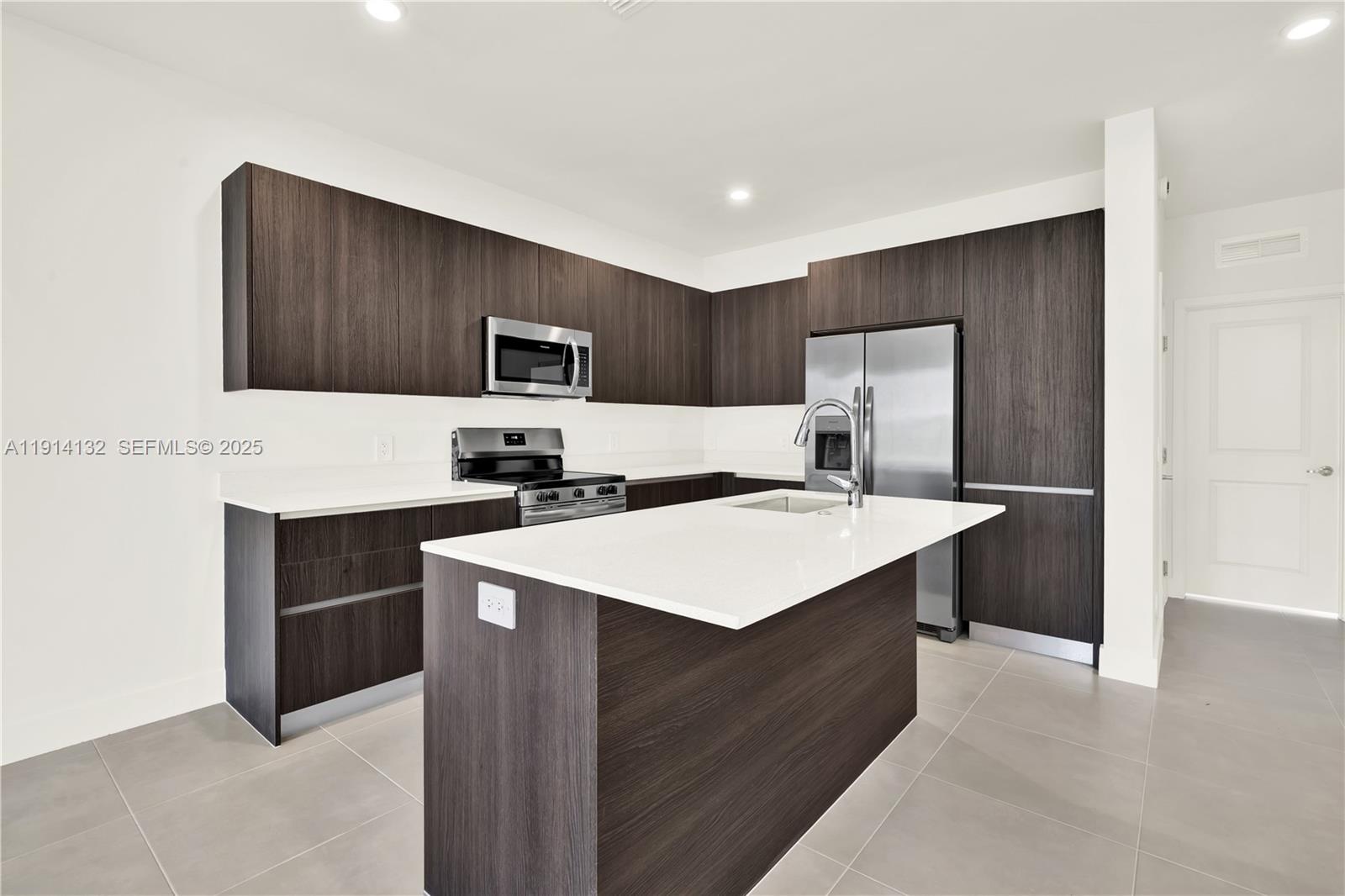 34520 Southwest 191st Court, Unit 34520 Homestead, FL 33034 - Photo 6 of 37 a kitchen with kitchen island a sink refrigerator and microwave