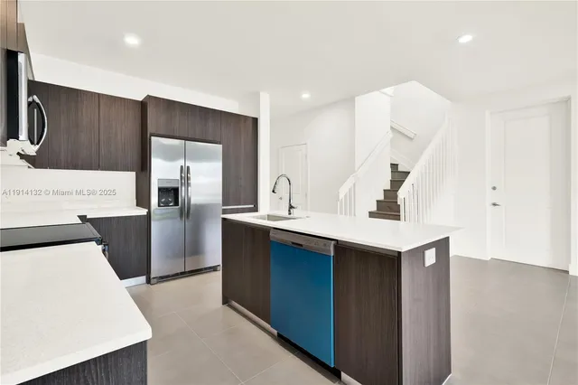 a kitchen with a sink a refrigerator and cabinets