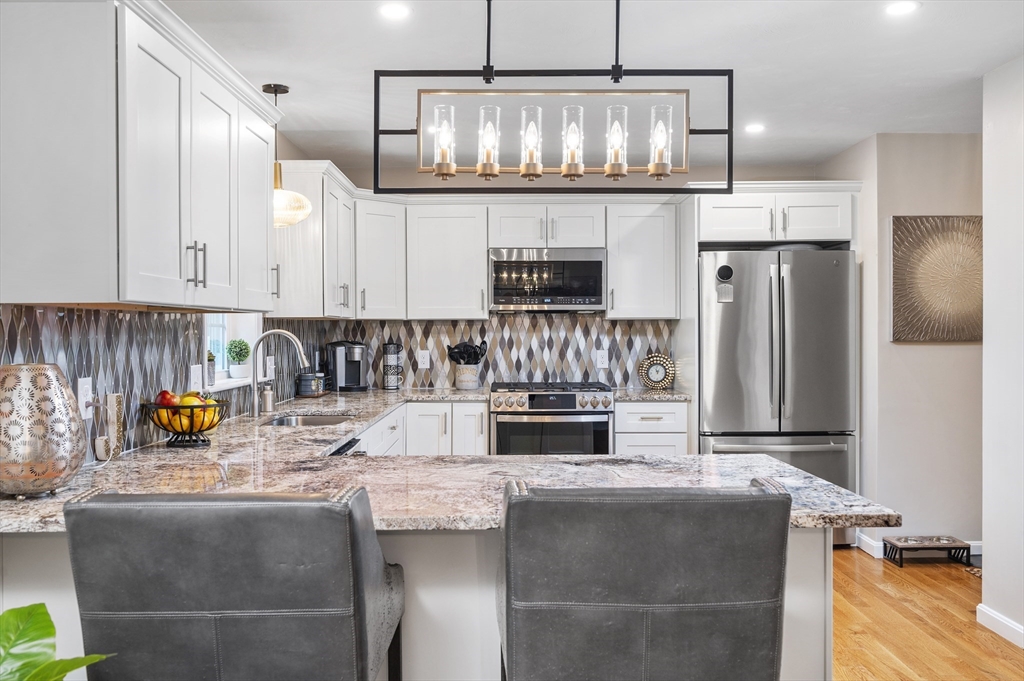 16 Farnum Street, Unit 16 Uxbridge, MA 01569 - Photo 11 of 34 a kitchen with granite countertop a stove and white cabinets