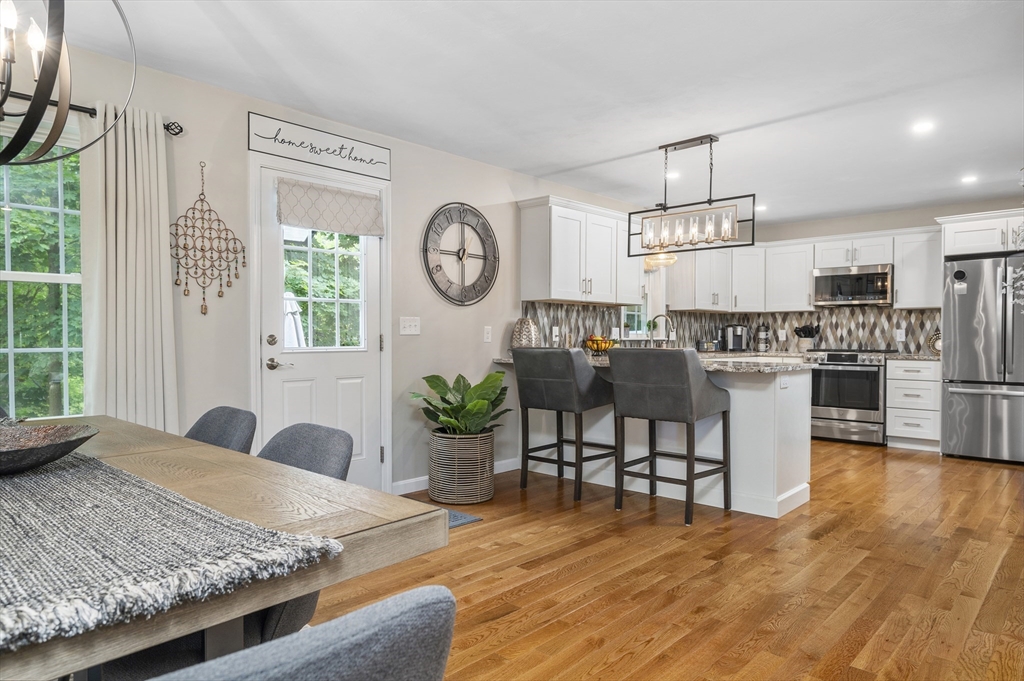 16 Farnum Street, Unit 16 Uxbridge, MA 01569 - Photo 9 of 34 a open kitchen with granite countertop a stove a sink a dining table and chairs