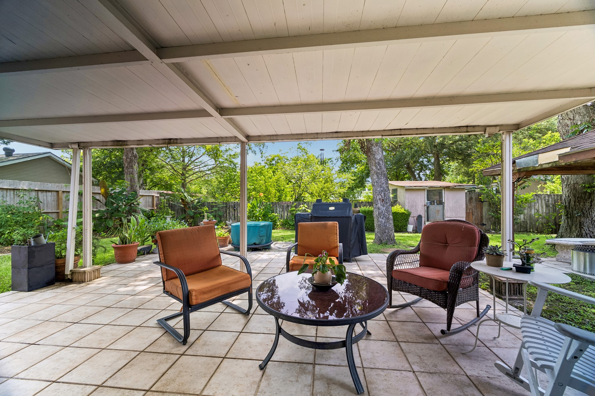 413 Mebane Lane Rosenberg, TX 77471 - Photo 25 of 30 This inviting patio features a covered seating area in the backyard with mature trees and a small shed. Perfect for outdoor relaxation and entertaining.
