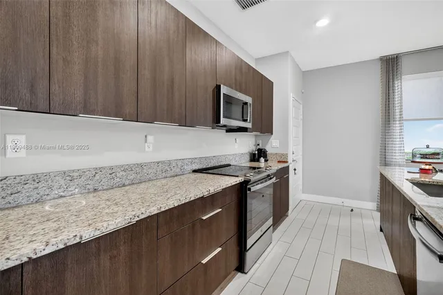 a kitchen with stainless steel appliances granite countertop a sink a stove top oven a refrigerator with wooden cabinets and floor